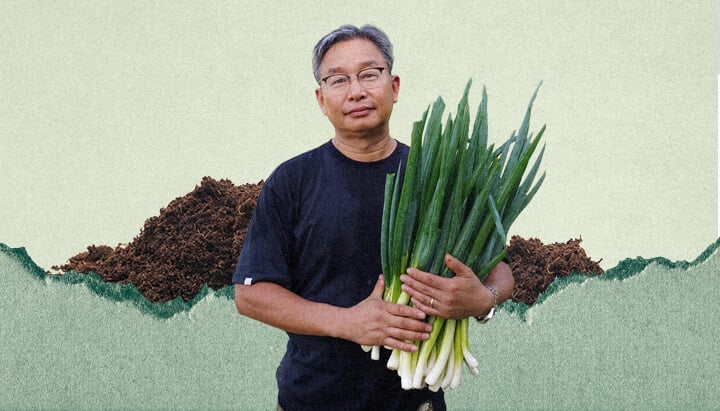 A man named Youngsang Cho is holding a bunch of green onions. He is standing in front of a pile of dirt.